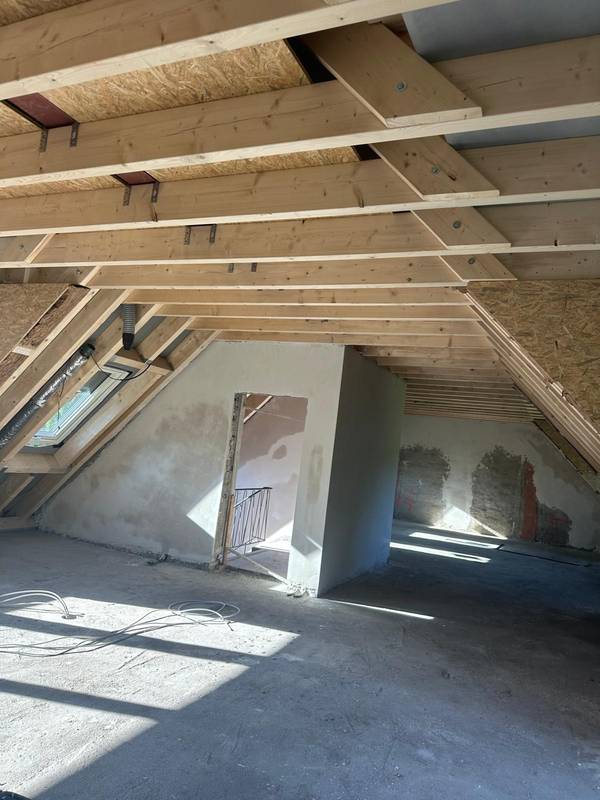Offener Dachstuhl mit Holzsparren vor dem Ausbau